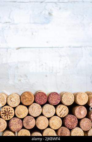 Fila orizzontale di tappi, su un tavolo bianco di legno con molto spazio negativo sopra. Utile per pubblicità su vini, enoteche, ristoranti e per v Foto Stock