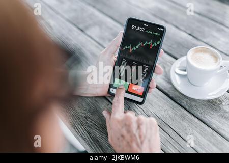 Donna anziana che utilizza l'applicazione per cellulare per acquistare criptovaluta Foto Stock