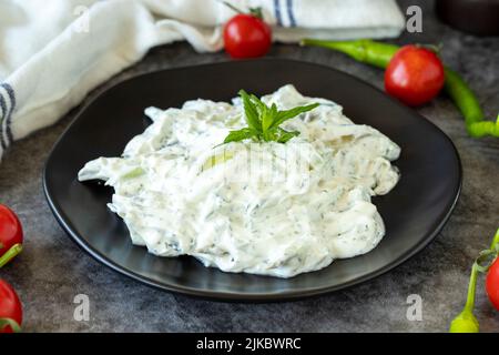 Antipasto di yogurt fresco. Tzatziki asciutto su sfondo scuro. Cacik a base di menta, insalata e yogurt. Pasti sani. Nome locale kuru cacik .Close up Foto Stock