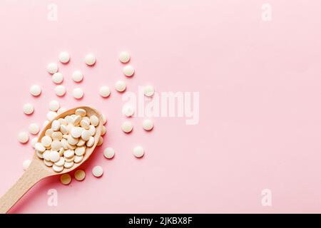 Mucchio di pillole bianche su sfondo colorato. Compresse sparse su un tavolo. Pila di capsule rosse di gelatina molle. Vitamine e supplementi dietetici concetto. Foto Stock