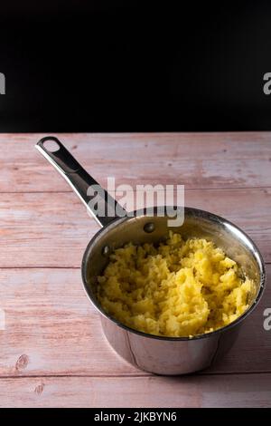 Purea di patate purè in padella d'argento su sfondo di tavolo di legno Foto Stock