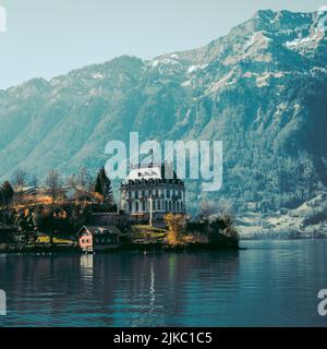 Il castello di Iseltwald sull'isola del Lago di Brienz con le montagne sullo sfondo Foto Stock