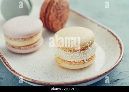 Macaron francesi colorati su piatto su sfondo blu Foto Stock