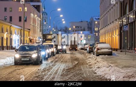 Auto su una strada innevata in una serata invernale. Messa a fuoco soft. Foto Stock