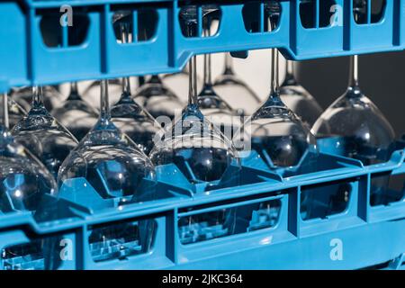 Scatole in plastica blu con wineglasses lucenti per ristorante in piedi capovolto e luce riflettente Foto Stock