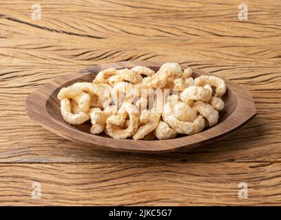 Crackling di pelle di maiale fritto su un piatto su tavola di legno. Foto Stock