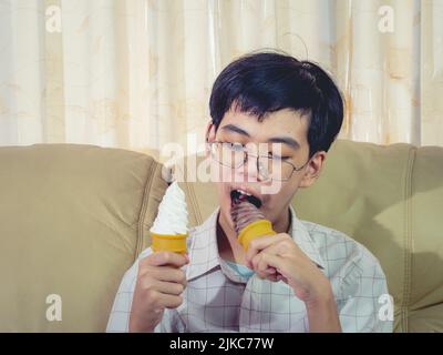 Asia ragazzo tenere gelato alla vaniglia in cialde cono felice sorridente e mangiare delizioso in estate con divertirsi e buon umore. Foto Stock