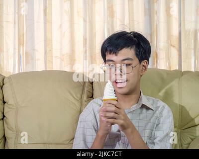 Asia ragazzo tenere gelato alla vaniglia in cialde cono felice sorridente e mangiare delizioso in estate con divertirsi e buon umore. Foto Stock