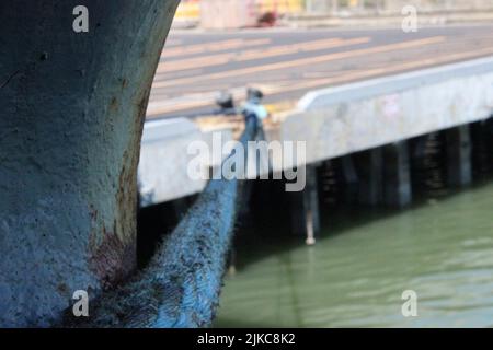 Una messa a fuoco poco profonda di una corda spessa che si collega con una banchina sull'acqua Foto Stock