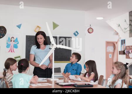Scuola elementare STEM Robotics Classroom Gruppo diversificato di bambini costruzione e programmazione di mulino a vento ecologia robot concetto. Insieme parlando e. Foto Stock