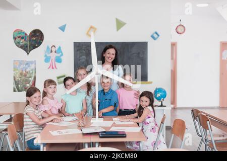Scuola elementare STEM Robotics Classroom Gruppo diversificato di bambini costruzione e programmazione di mulino a vento ecologia robot concetto. Insieme parlando e. Foto Stock