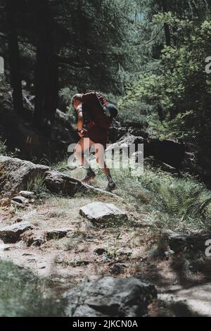 Giovane escursionista femminile che cammina in salita con un pesante zaino pronto per la notte Foto Stock