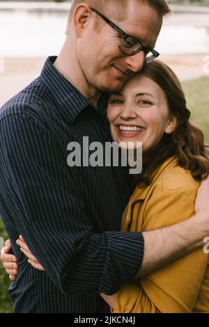 Adulto sposato coppia abbraccia e sorride su Lakeshore Foto Stock