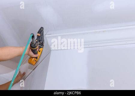 Un'unghia ad aria è stata usata dal falegname per installare la modanatura della corona d'angolo del soffitto Foto Stock