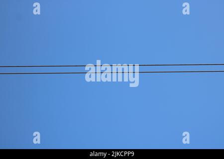 Linee di trasmissione della potenza contro il cielo blu profondo con spazio di copia Foto Stock