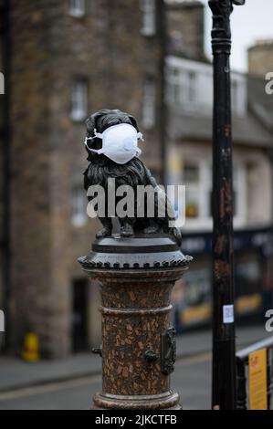 Statua del cane Greyfriars Bobby con maschera facciale durante il blocco pandemico di Covid 19 a Edimburgo, Scozia, Regno Unito Foto Stock