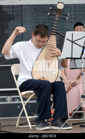 Un membro del Chinese Music Ensemble di New York suona la pipa, uno strumento tradizionale cinese. All'Hong Kong Dragon Boat Fest di Queens, New York. Foto Stock