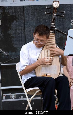 Un membro del Chinese Music Ensemble di New York suona la pipa, uno strumento tradizionale cinese. All'Hong Kong Dragon Boat Fest di Queens, New York. Foto Stock