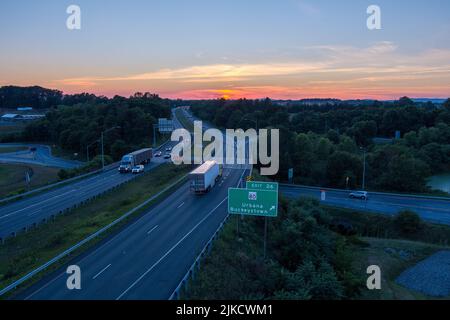 Il sole tramonta sull'Interstate 270 a Urbana, Frederick County, Maryland. Due rimorchi del trattore passano in direzioni opposte. Foto Stock