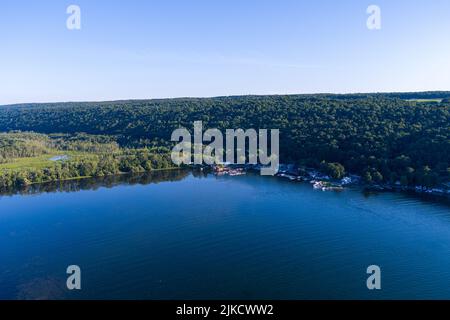 Il sole nel tardo pomeriggio splende sul lago Owasco vicino a Moravia, nella contea di Cayuga, New York. Un piccolo porto turistico si trova in centro. Foto Stock