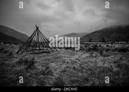 Un colpo in scala di grigi di una tribù nomade teepee struttura su un campo rurale in Mongolia Foto Stock