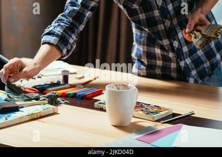 strumenti per artisti pennelli marcatori mani posto di lavoro Foto Stock