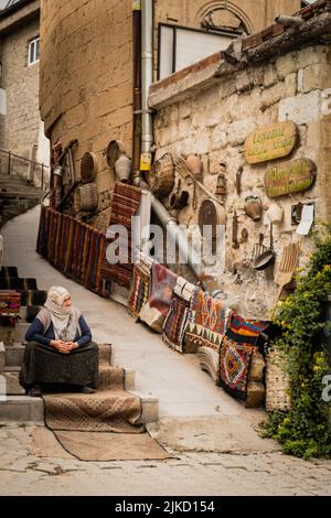 Una foto verticale di una vecchia donna che vende tappeti per strada a Goreme, in Cappadocia Foto Stock