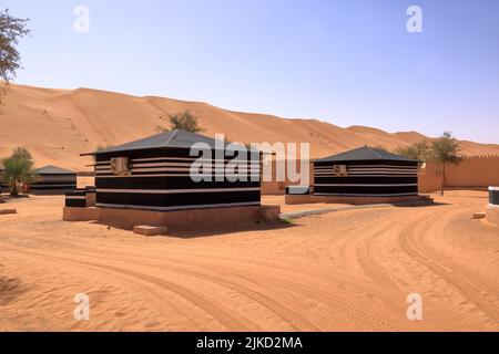 Campeggio in stile beduino accanto ad una enorme duna di sabbia nel deserto di Wahiba Sands in Oman. Foto Stock