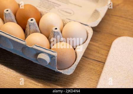 Un pacchetto di uova fresche di fattoria eco-free gamma in cucina da vicino, dettaglio shot, scatola di cartone uovo contenitore su un tavolo di legno, primo piano, nessuno, nessuna gente Foto Stock