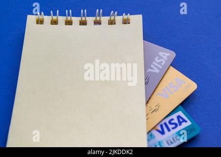 Mosca, Russia, Agosto 2019: Carte di credito: Visa, Visa gold, Visa electron guardare fuori da un taccuino con spazio per il testo. Tutto su sfondo blu scuro. Foto Stock