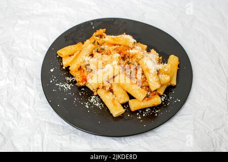 Pasta bolognese con salsa ragu e parmigiano su un piatto nero isolato su bianco Foto Stock