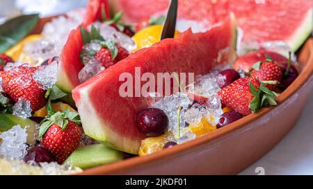 Frutta fresca di fondo. Vista dall'alto delle fette di frutta fresca sul ghiaccio. Melone, anguria, frutti rossi. Foto Stock