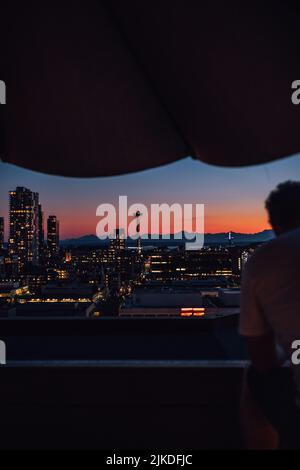 Uomo che guarda fuori al tramonto con lo skyline di Seattle dal ponte sul tetto di Capitol Hill Foto Stock