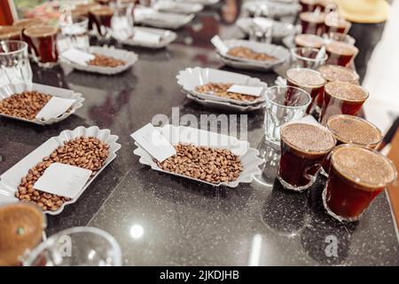 Bicchieri e fagioli da caffè sul tavolo pronti per una degustazione al chiuso Foto Stock