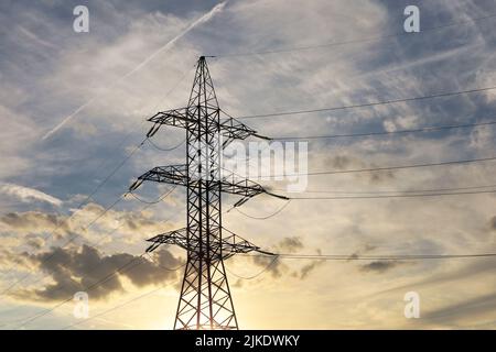 Silhouette di torre ad alta tensione con fili elettrici sullo sfondo del cielo e delle nuvole del tramonto. Linee di trasmissione dell'elettricità, concetto di alimentazione Foto Stock