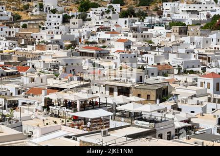 Lindos, Rodes, Greece - May 2022: Aerial view of restaurants and other whitewashed buildings in the town of Lindos Foto Stock