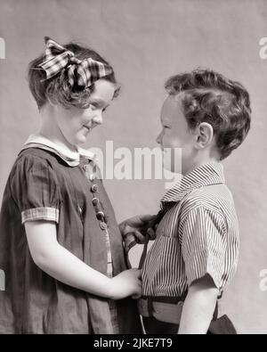 1930S SORRIDENTE GRANDE SORELLA AIUTANDO PICCOLO FRATELLO LEGARE IL SUO CRAVATTA - J216 HAR001 HARS COMPIACENTI FAMIGLIE GIOIA LIFESTYLE SODDISFAZIONE FEMMINE FRATELLI STUDIO SHOT HOME VITA COPIA SPAZIO AMICIZIA MEZZA LUNGHEZZA PERSONE CURA MASCHI FRATELLI FRATELLI FRATELLI FRATELLI FRATELLI SORELLE FELICITÀ ALLEGRO SUO ORGOGLIO COLLANTE FRATELLI SORRISI CONNESSIONE AMICHEVOLE GIOIOSO ELEGANTE SOSTEGNO COOPERAZIONE CRESCITA INSIEME GIOVANE GRANDE SORELLA NERO E BIANCO ETNIA CAUCASICA HAR001 POCO FRATELLO VECCHIO STILE Foto Stock