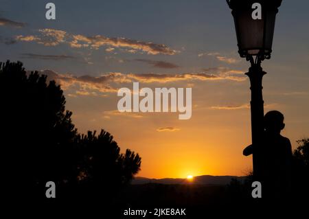 Silhouette di un bambino che gioca in un palo leggero durante il tramonto al Tempio di Debod a Madrid Foto Stock