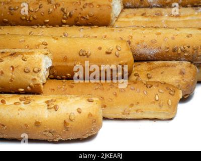 Biscotti al sesamo su sfondo bianco. I biscotti sono allungati sotto forma di bastoncini. Prodotti del pane. Prodotti a base di farina per spuntini. Un sacco di torte fatte in casa Foto Stock