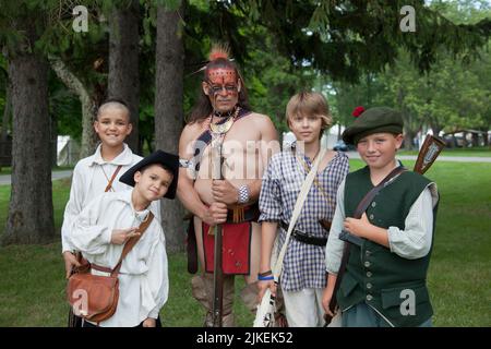 Dei bambini e un guerriero irochese vestito con abiti d'epoca. Old Fort Niagara state Park, New York Foto Stock