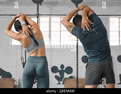 Coppia fitness attiva e sportiva stretching o partner palestra e amici pronti ad allenarsi insieme. Vista posteriore dell'allenatore maschile e dell'atleta femminile Foto Stock