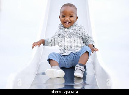 Non c'è paura quando si ha divertimento. Un bambino che gioca sullo scivolo nel parco. Foto Stock