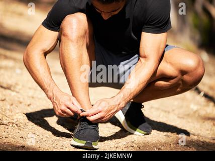 Indossa le scarpe da running e corri al mondo. Un uomo che lega le scarpe mentre sei fuori per una corsa. Foto Stock