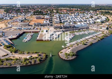 Zwenkau, Germania. 19th luglio 2022. Un porto e nuovi edifici residenziali sono stati costruiti a Capo Zwenkau sul lago omonimo. L'ex miniera di lignite a cielo aperto di Zwenkau ha dato origine al più grande lago della regione di Lipsia, che copre un'area di quasi 10 chilometri quadrati. Dal 2011 è in costruzione un nuovo quartiere sulla riva Zwenkau, che offre spazio per vivere e lavorare. (Vista aerea con drone) Credit: Jan Woitas/dpa/ZB/dpa/Alamy Live News Foto Stock