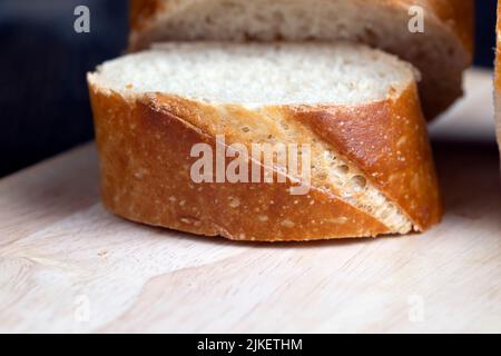 affettato a pezzetti una lunga baguette con una crosta croccante, tagliato a fettine di dolci di grano fresco baguette Foto Stock