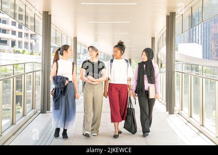 Gruppo di amici studenti universitari multirazziali che camminano insieme in sala. Torna al concetto di college. Foto Stock