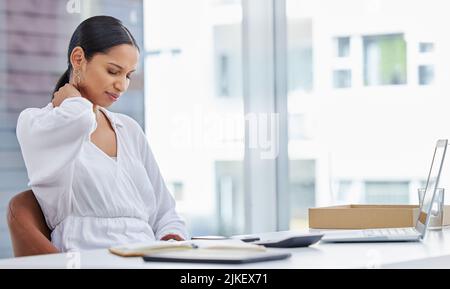 Oggi mi sono riunito al collo e mi ha portato fastidio. Una giovane donna d'affari seduta su una scrivania sentendosi sforzata al collo in un ufficio moderno. Foto Stock