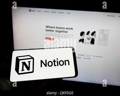Persona che tiene il cellulare con il logo della società di software degli Stati Uniti, la nozione Labs Inc. Sullo schermo di fronte al sito web aziendale. Mettere a fuoco sul display del telefono. Foto Stock