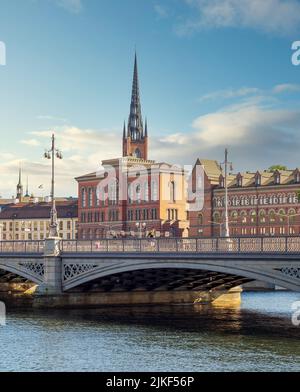 Vecchio Archivio Nazionale, o Gamla Riksarkivet, e gli edifici di Norstedt, che si affacciano Vasabron o ponte Vasa e il fiume Norrstrom, con la torre della Chiesa Riddarholmen sullo sfondo, Stoccolma, Svezia Foto Stock