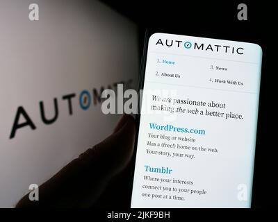 Persona che detiene il cellulare con il sito web della società distribuita statunitense Automattic Inc. Sullo schermo di fronte al logo. Concentrarsi sul centro del display del telefono. Foto Stock